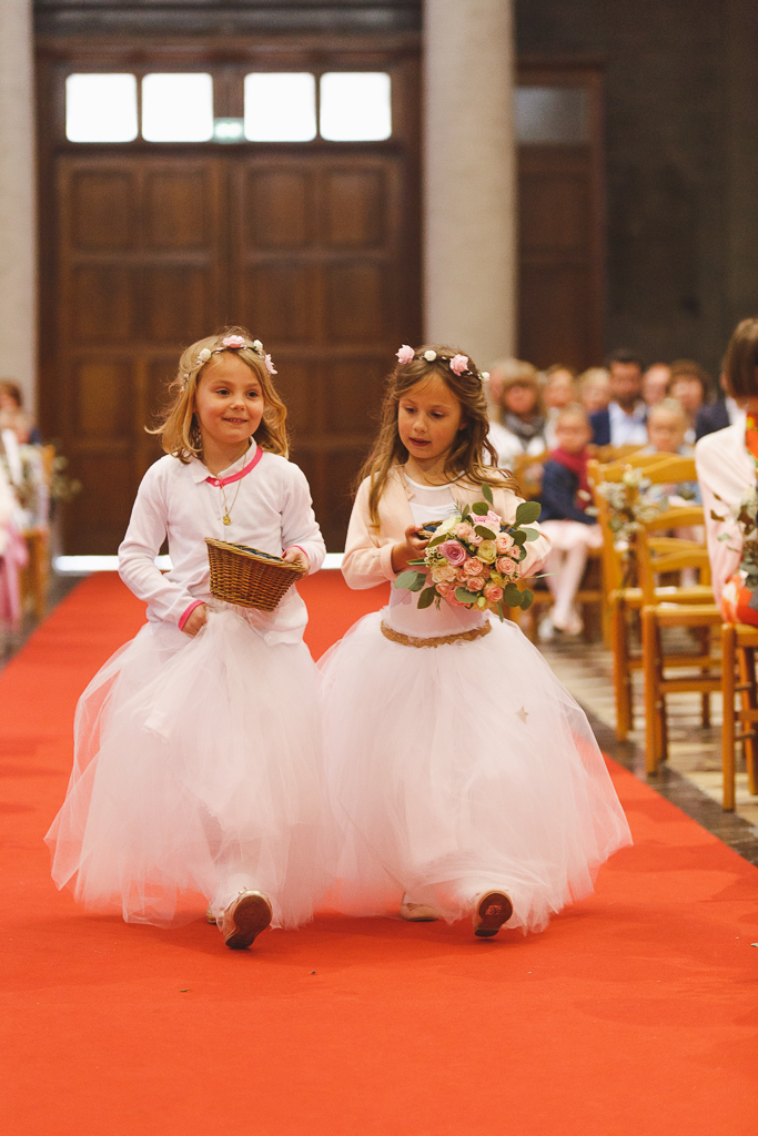 deux filles d'honneur tenue de cérémonie en tulle marche sur tapis rouge église panier en osier et bouquet à la main Fred Laurent photographe mariage 