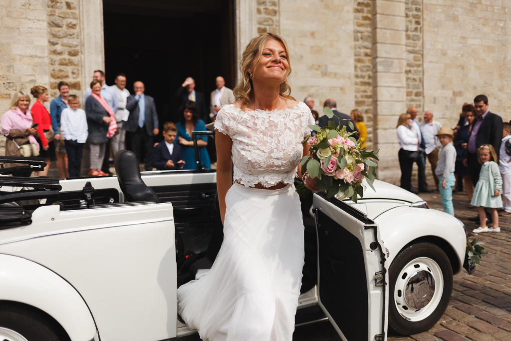 mariée sortant de Coccinelle blanche devant église Boulogne sur Mer bouquet pastel roses eucalyptus à la main
