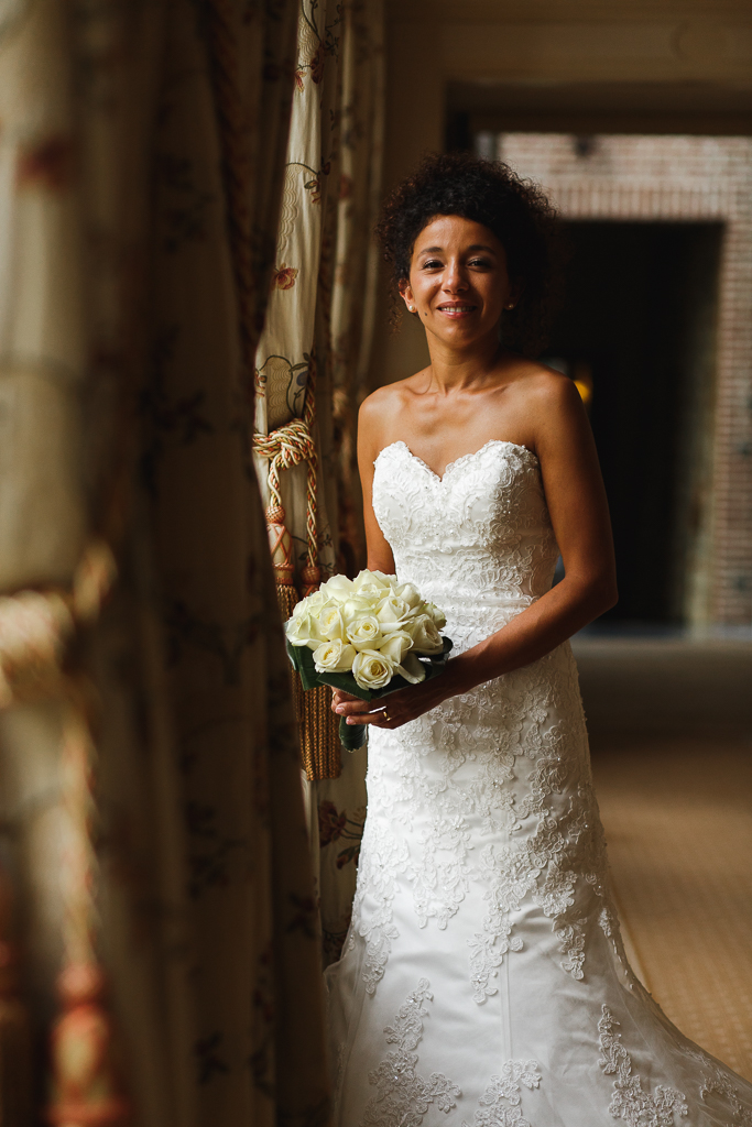 mariee avec bouquet de roses blanches dans couloir mariage au domaine de la chartreuse a gosnay