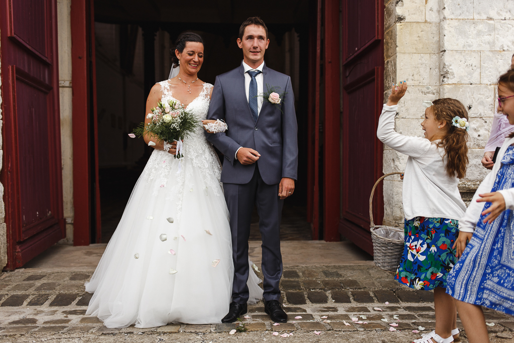 demoiselles d'honneur avec paniers lancent pétales de roses sur jeunes mariés sortie église Licques