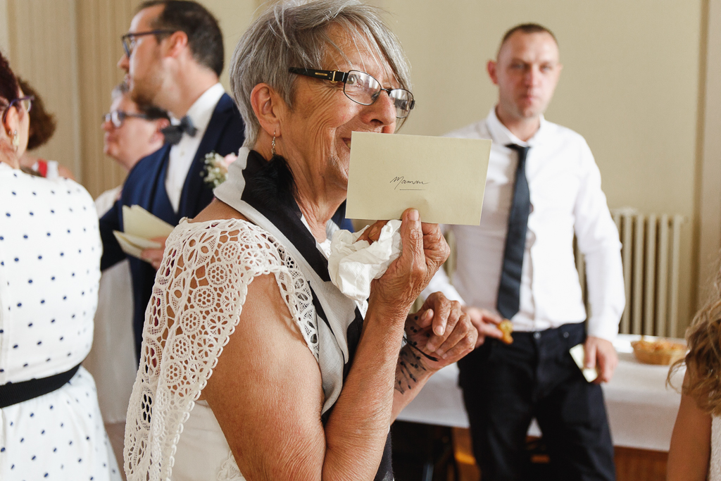 invitée tenant enveloppe surprise indiquant lieu de réception reportage mariage Hauts-de-France