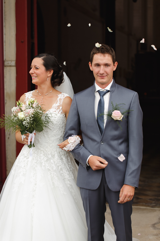 couple à la sortie de l'église pétales de roses mariage Trois Pays