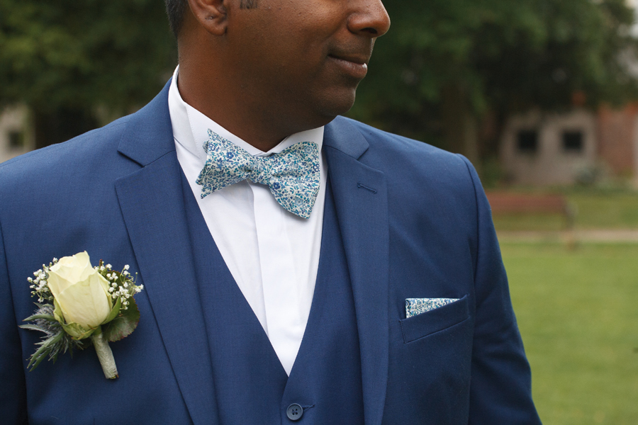 détail costume marié bleu noeud papillon et pochette liberty tons bleus boutonnière rose jaune pâle gypsophile et chardon