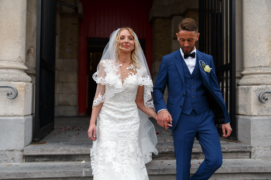 mariés descendent marches après cérémonie église dans Nord tout sourire photographe mariage Lille