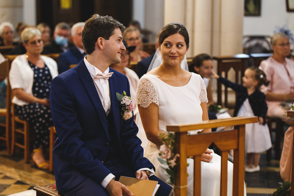Echange de regards entre le marié et son épouse. Photo du couple lors de la cérémonie religieuse. Photographe professionnel Nord.