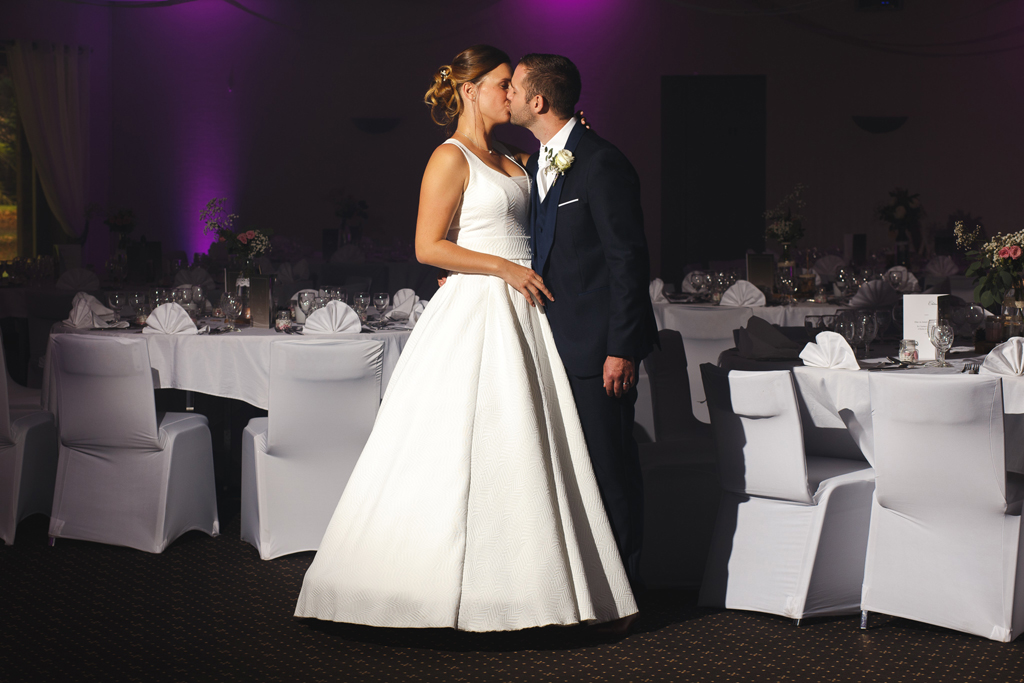 Les mariés s'embrassent en salle de réception. Photographie de mariage en région Nord