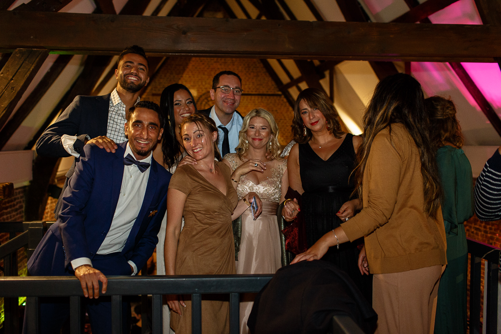 Photo de groupe sur le vif mariage Villeneuve d'Ascq à La Terrasse du Héron restaurant salle de réception mariages. Les invités des mariés photographiés au balcon. Photographe mariage professionnel région de Lille
