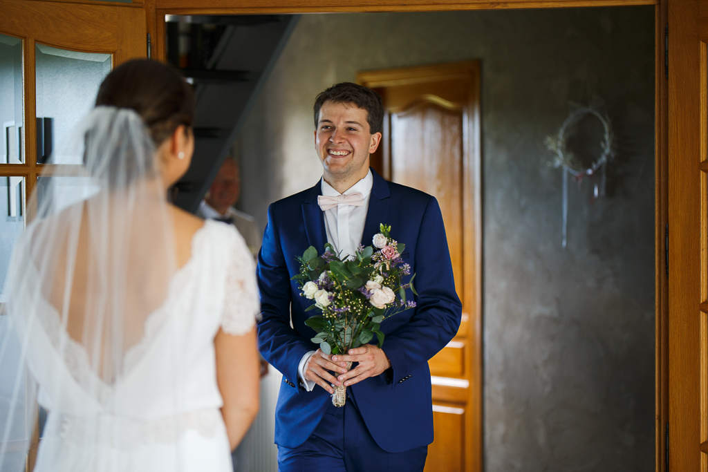 Remise du bouquet par le marié et découverte de la robe de la mariée. Moment d'émotion et regards. 