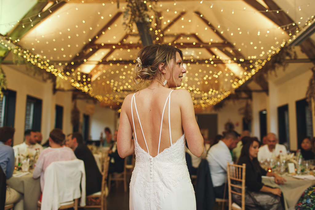 Photo de la mariée de dos en début de soirée. Décorations lumineuses et ambiance festive à la Ferme St Chrysole. Reportage photo  mariage à Wambrechies.