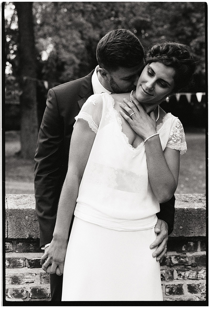Portrait des mariés en argentique. Couple élégant debout contre un muré. Photo noir et blanc dans un style rétro.