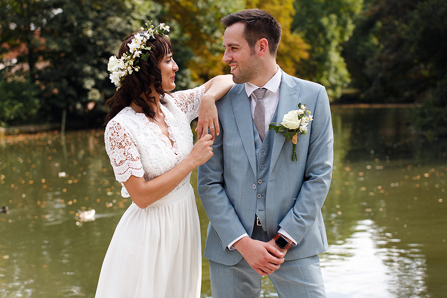 Mariage champêtre en petit comité en Belgique. Photo des mariés devant un bassin, scène décontractée et romantique. Complicité du couple et photo naturelle. Reportages de qualité dans le Nord.